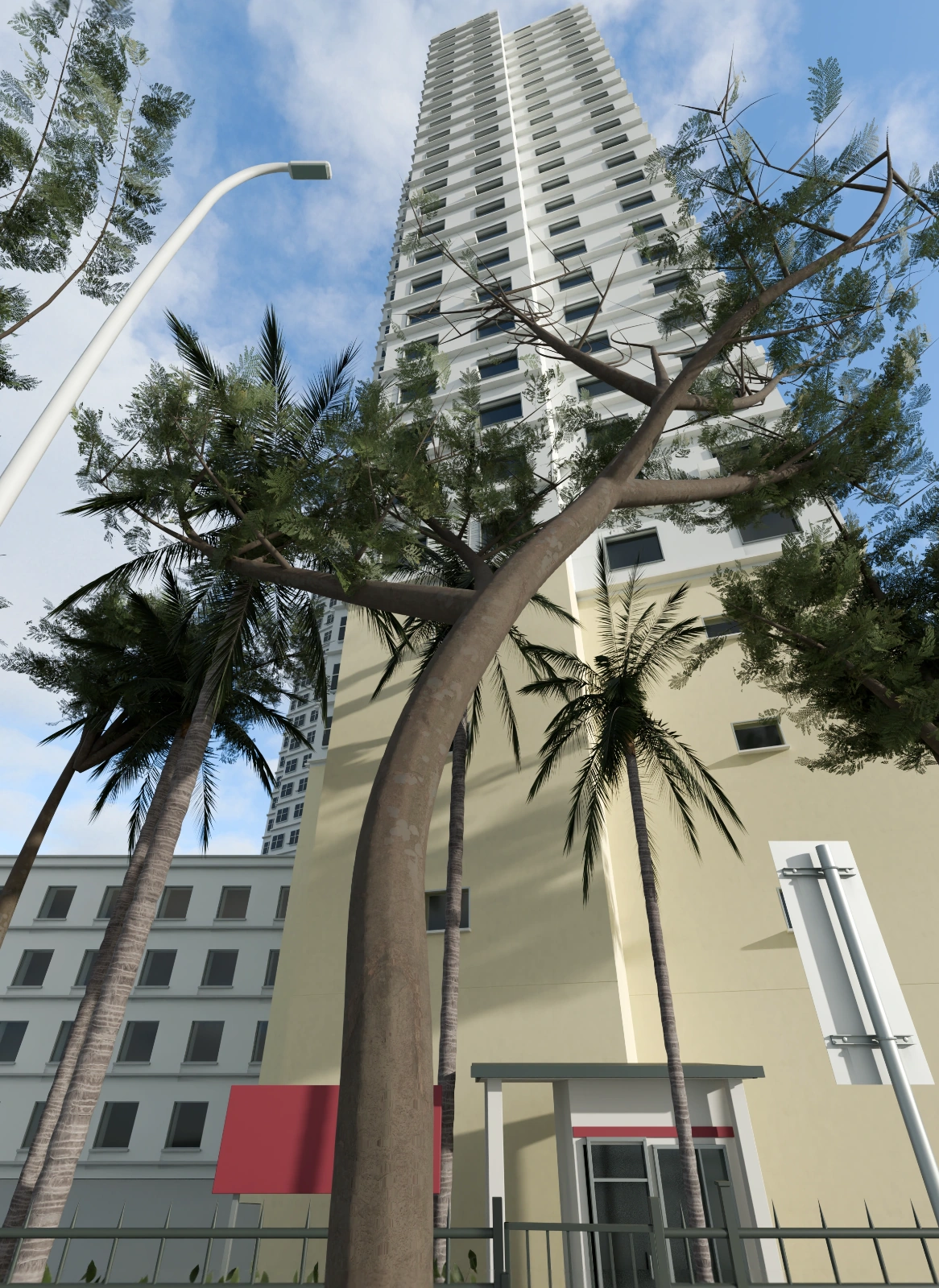 仰视街景，白色与浅黄色高层建筑向上延伸，前景可见树干、棕榈、路灯与沿街围栏，背景为蓝天云层